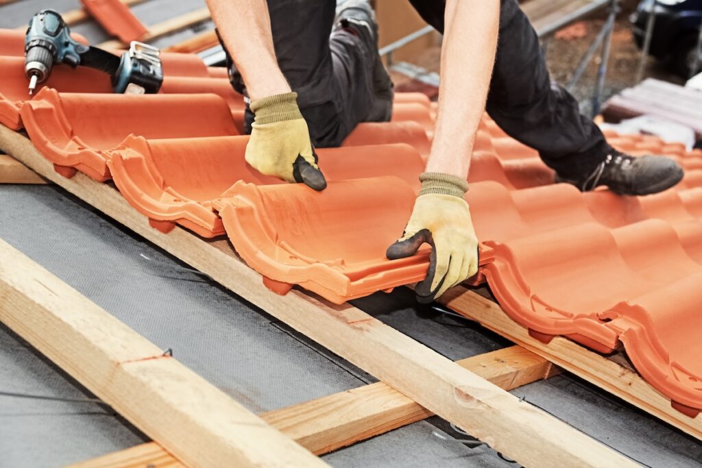 Roofer installing orange tile roofing