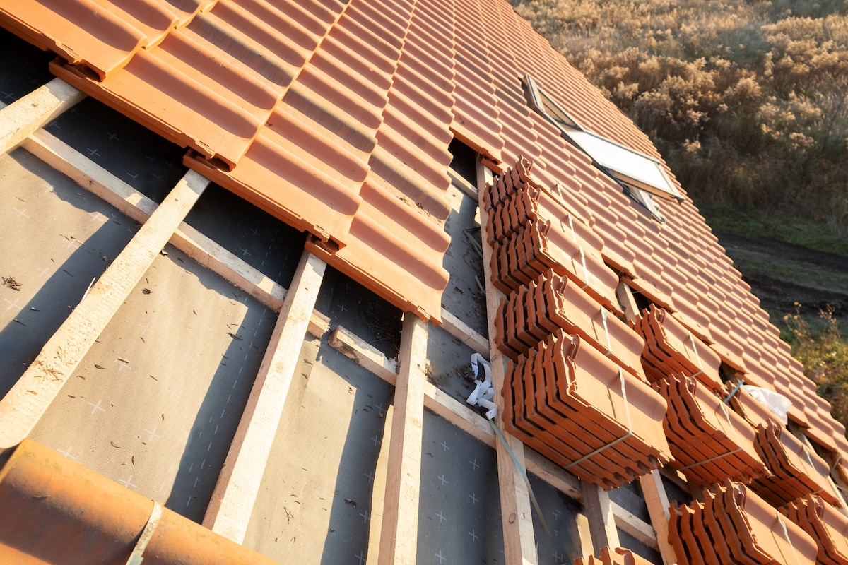 Stacks of yellow ceramic roofing tiles for covering residential building roof under construction.
