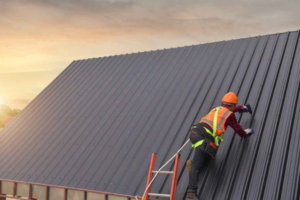 Roofer installing commercial metal roofing outside